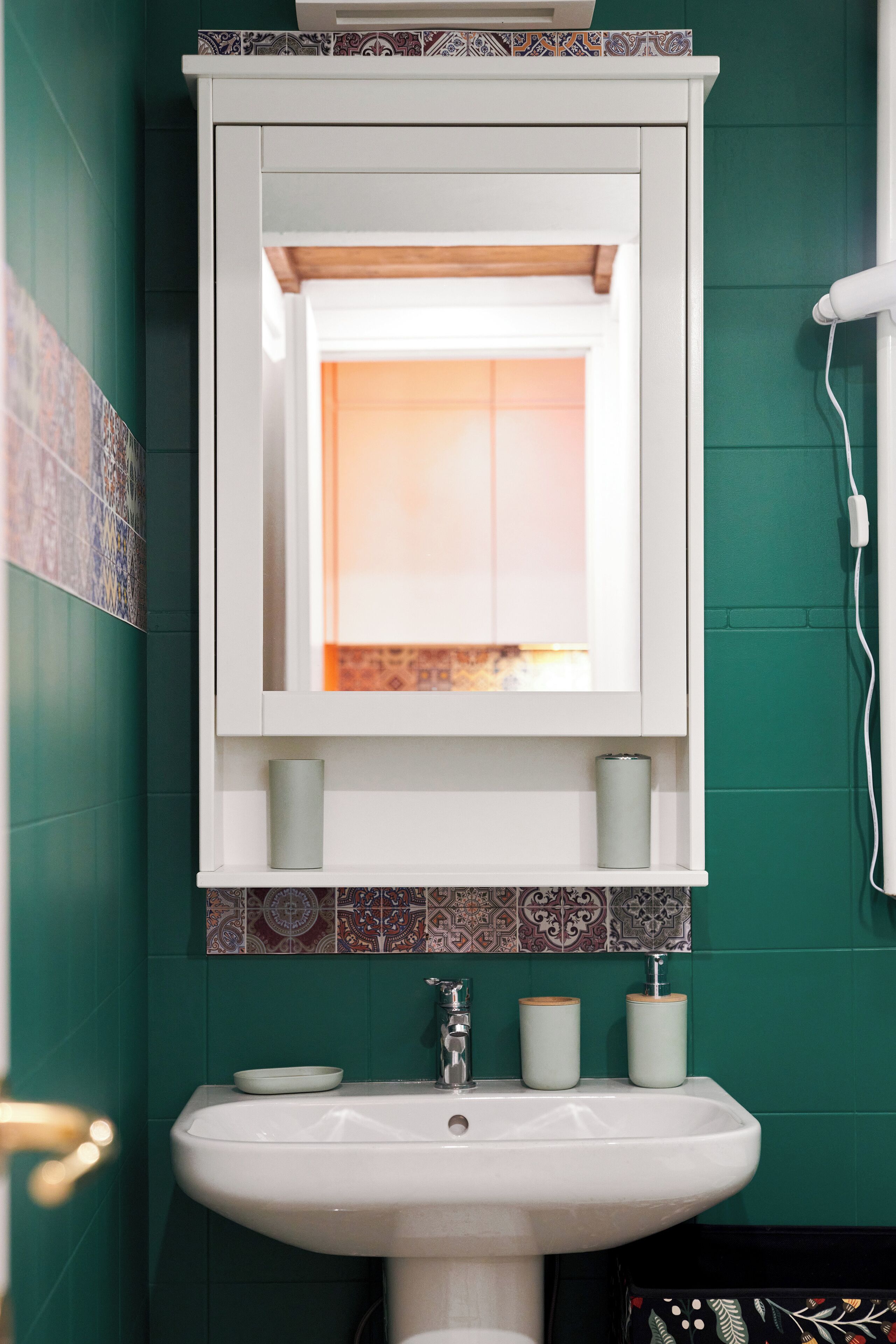 Ein Badezimmer mit einem weißen Waschbecken, einem Spiegel darüber und einem Fenster mit Sonnenuntergangsblick.