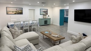 Una sala moderna con sofá, mesa de centro, mesa de comedor y zona de cocina.
