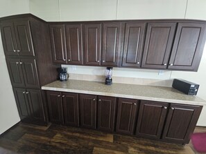 Una cocina con armarios de madera oscura, encimera de granito y cafetera.