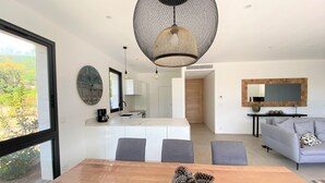 Ein modernes Wohnzimmer mit einem Holzesstisch, grauen Sofas und einem großen Fenster.