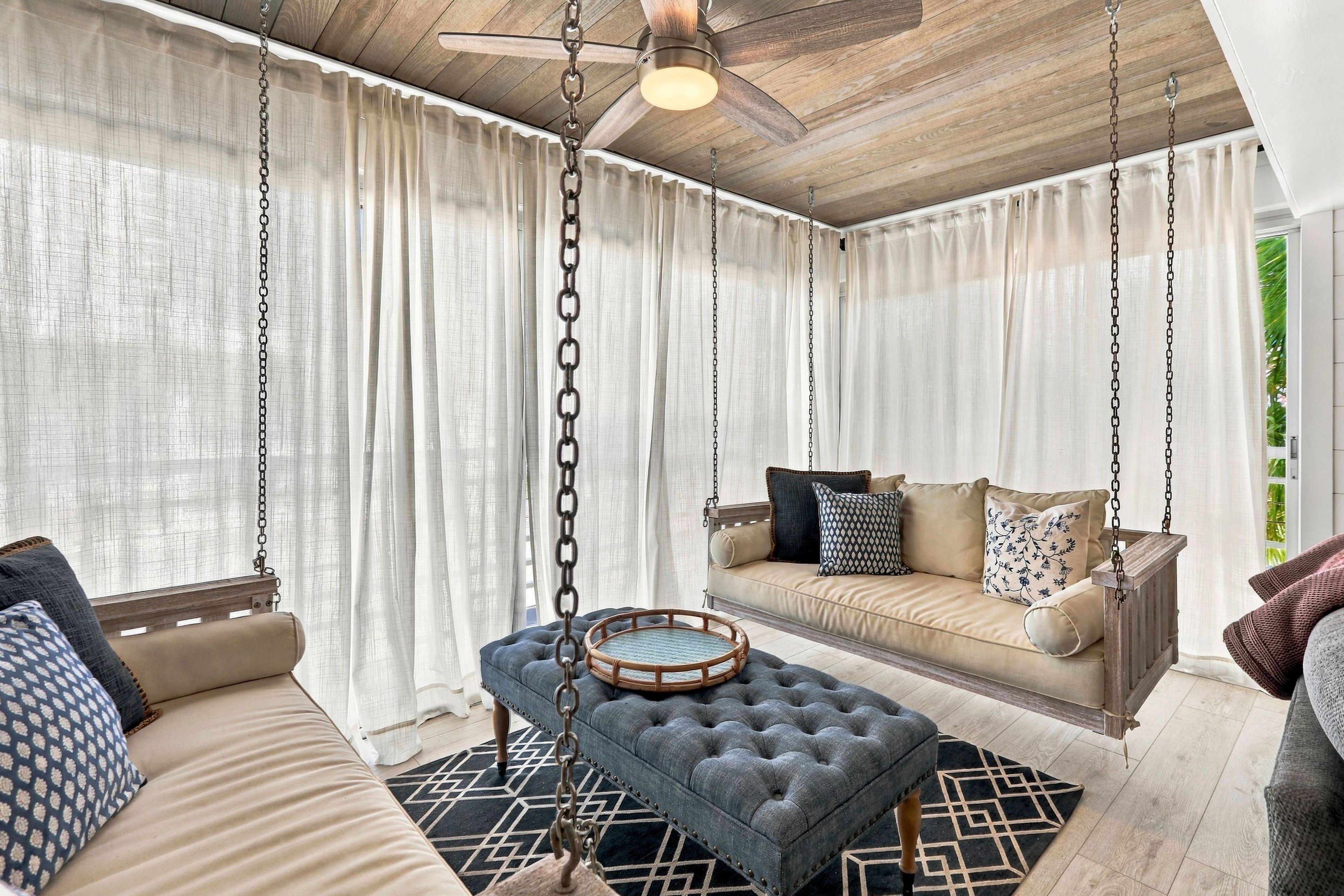 A room with a hanging swing chair, a sofa, and a patterned rug.