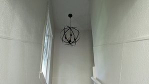 Una escalera con peldaños alfombrados, paredes blancas y una araña negra.