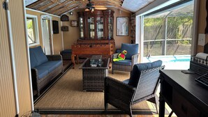 Et hyggeligt rum med trælofter, et stort træskab, en blå sofa, en fletstol og et lille bord.