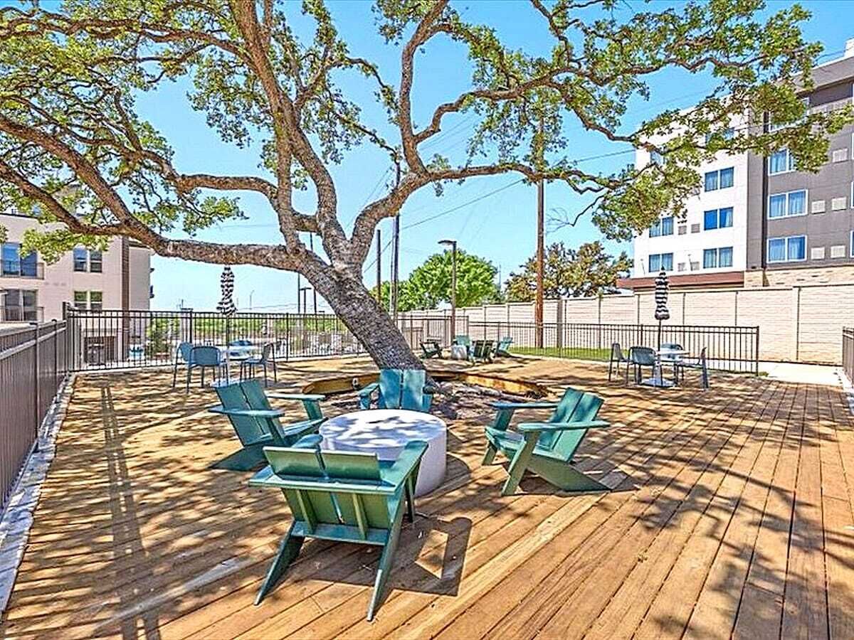Spacious backyard deck shaded by a large tree, featuring outdoor seating for relaxing, dining, or enjoying fresh air under the open sky.