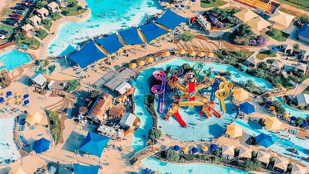 Vista aérea de un resort con múltiples piscinas, toboganes de agua y zonas de playa.