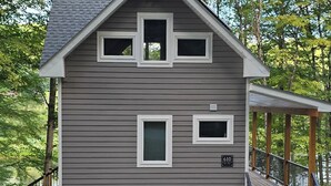 Une cabane de plain-pied avec un toit à pignon, une véranda et une allée gravillonnée.