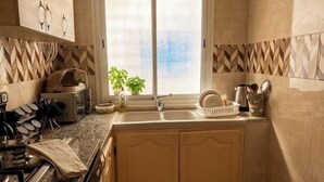 Cozinha compacta com máquina de lavar, pia e janela com vista.
