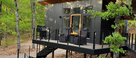 Una cabaña moderna con terraza, mobiliario exterior y una chimenea.