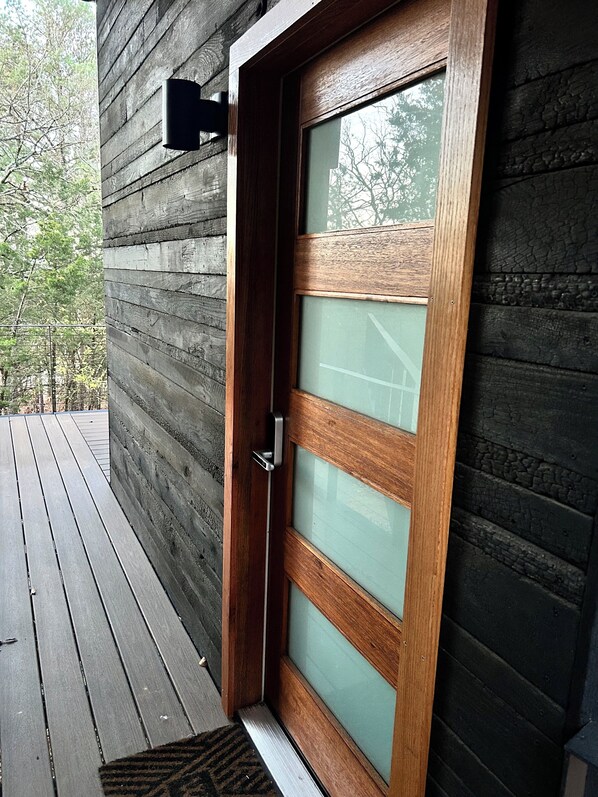 A wooden door with a glass panel, a metal handle, and a small rug at the base.