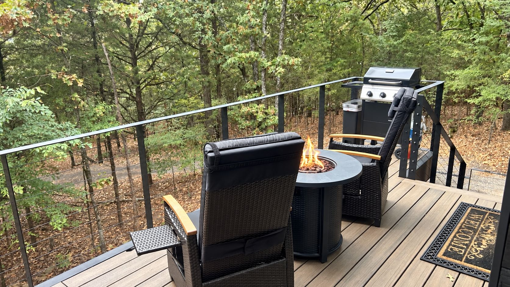 An outdoor deck with a fire pit, seating, and a grill.
