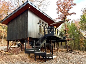 A cabin with a wooden exterior, a balcony, and a staircase leading to the upper level.