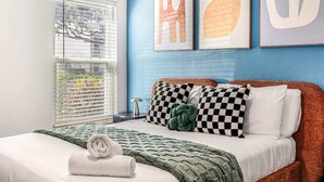 Une chambre à coucher avec un lit, des oreillers, une couverture et une fenêtre avec des stores.