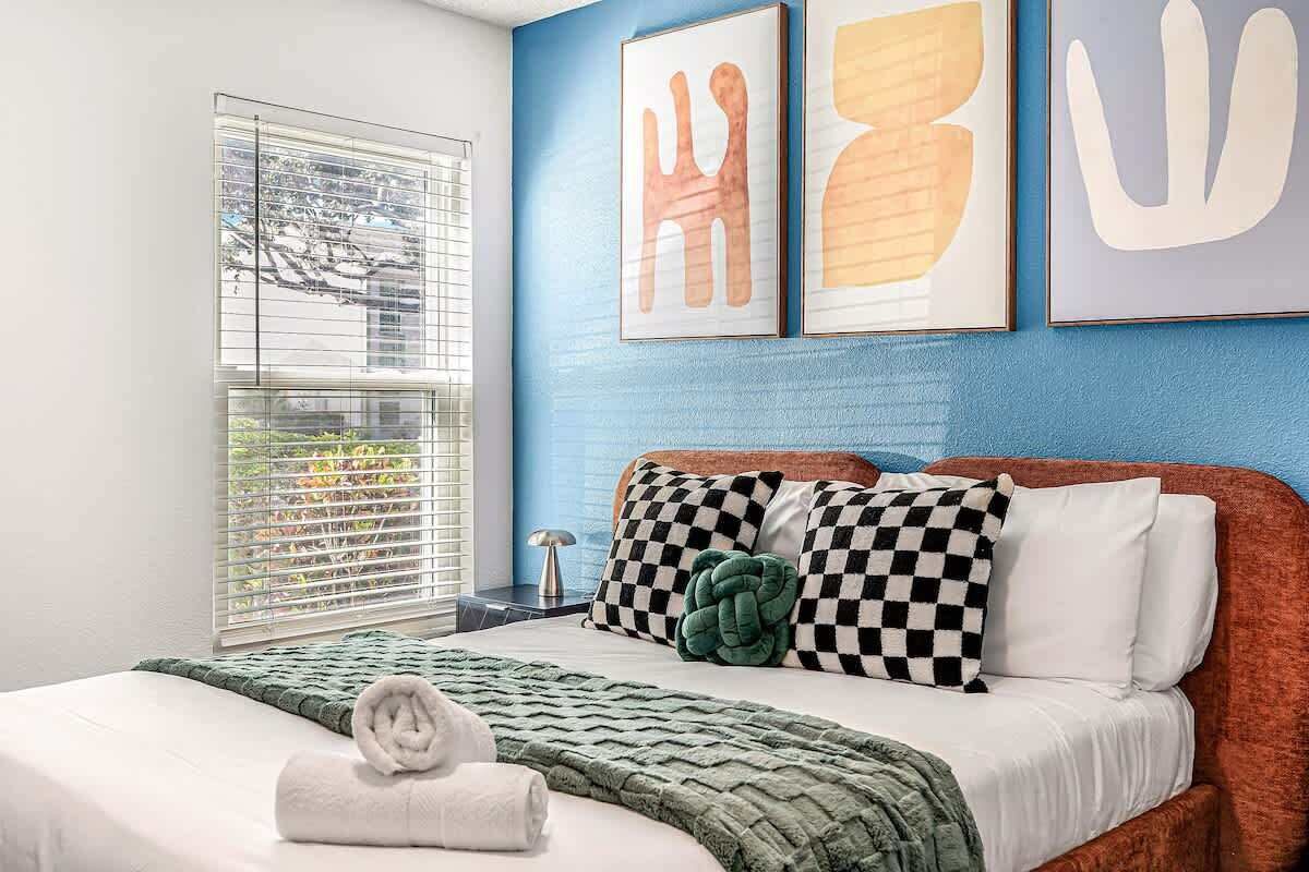 Une chambre à coucher avec un lit, des oreillers, une couverture et une fenêtre avec des stores.