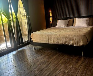 A bedroom with a large bed, wooden flooring, and a window with curtains. - Casa Jardines SLW, an ideal house for families or companies! (Saltillo)