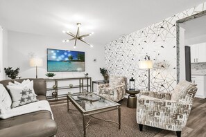 A modern living room with a flat-screen TV, patterned wall, and contemporary furniture. - Resort Like Winter Park Pool Home (Winter Park)