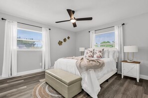 A bedroom with a bed, a ceiling fan, a bedside table with a lamp, and a window with curtains. - Resort Like Winter Park Pool Home (Winter Park)
