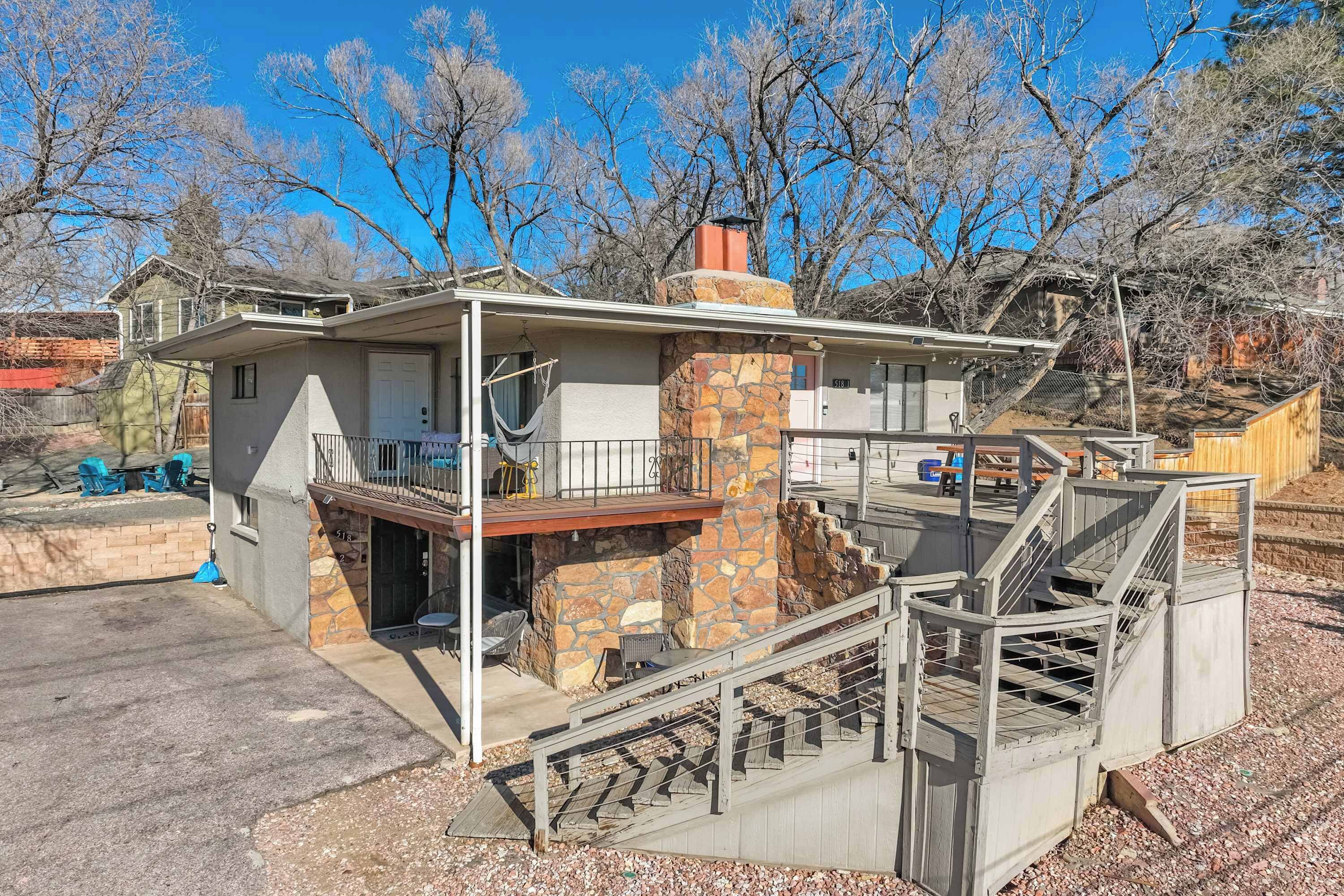 A two-story house with a stone chimney, a balcony, and a staircase leading to the upper floor.
