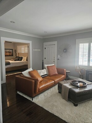 A living room with a brown leather sofa, a white fluffy rug, and a coffee table with a tray. - Stylish Craftsman Bungalow in the M Street Area (Dallas)