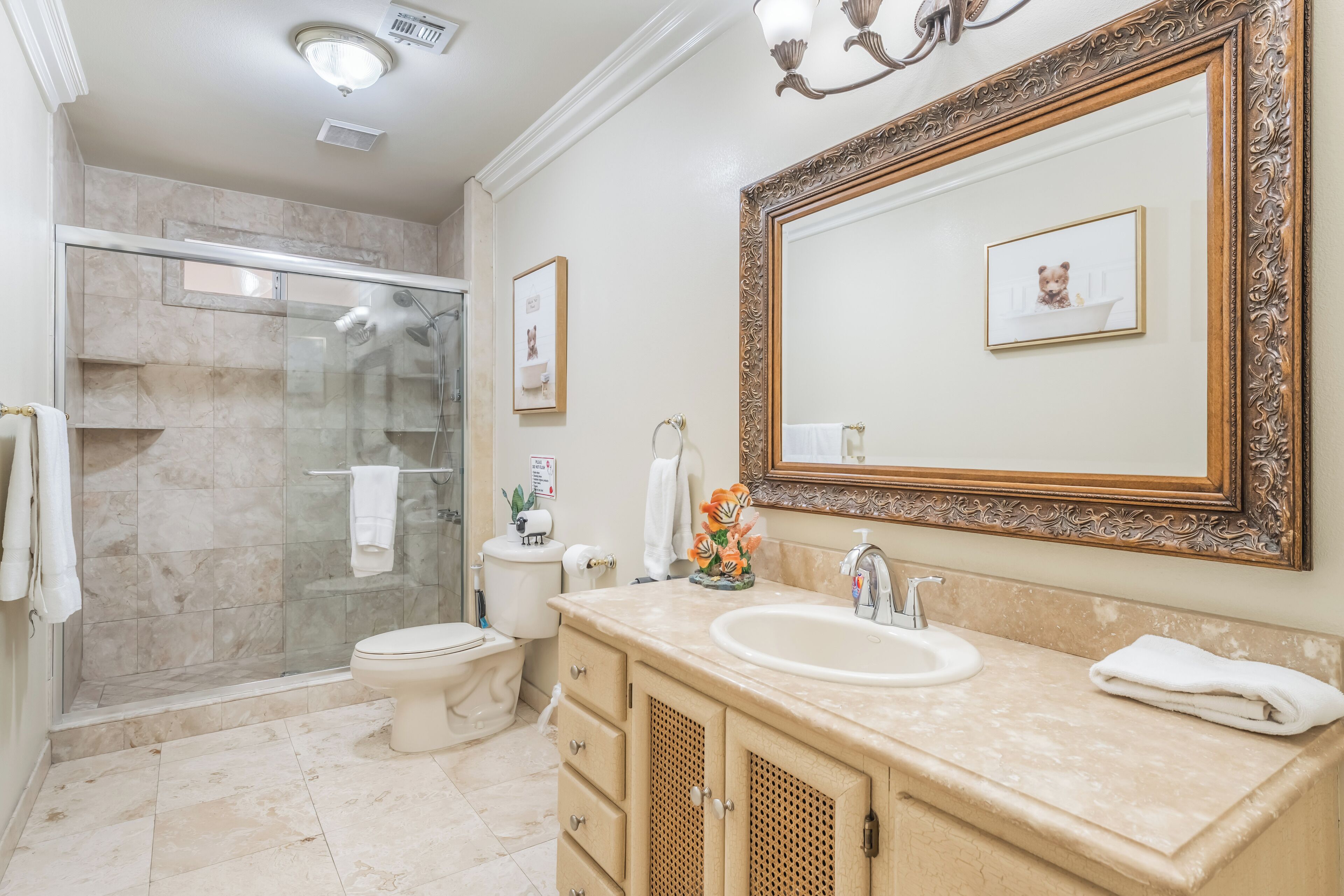 A bathroom with a glass-enclosed shower, a sink with a mirror, and a toilet.