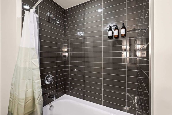Elegant tiled shower with built-in dispensers for shampoo, conditioner, and body wash — designed for a relaxing experience.