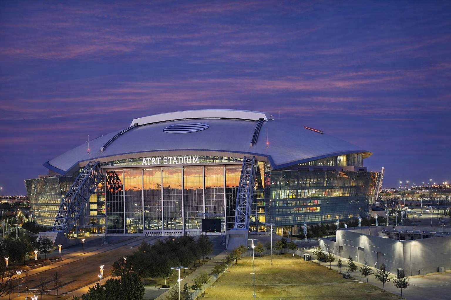 Un stade doté d’un grand toit incurvé et portant l’inscription « AT&T Stadium » sur sa façade.