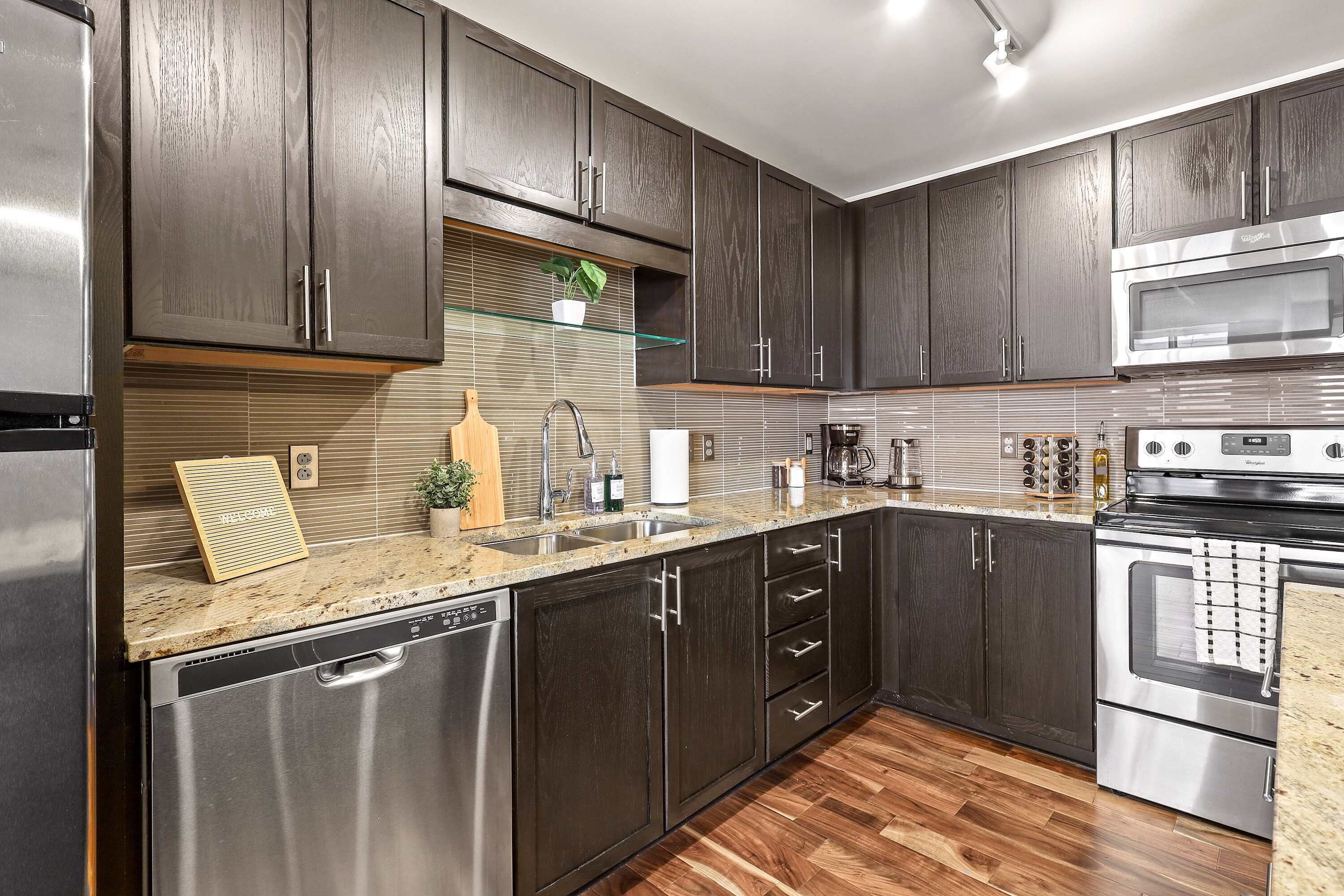 A modern kitchen with dark wood cabinets, stainless steel appliances, and a granite countertop.