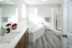 A modern bathroom with a large bathtub, a double sink, and a glass shower enclosure.