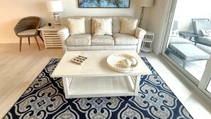 Ein Wohnzimmer mit Sofa, Couchtisch, Sessel und einem Bild an der Wand.