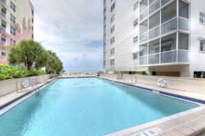 A rectangular swimming pool with a tiled edge, surrounded by a low wall. There are lounge chairs and a palm tree along the poolside. - Gateway Villas #298 - "Gateway Villa Retreat" 1 Bedroom Beach Front (Fort Myers Beach)