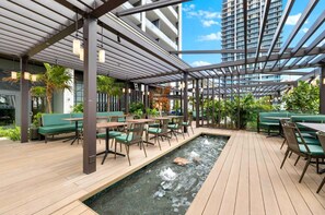 An outdoor patio with wooden flooring, green seating, and a small water feature. - 2105 - Modern studio with Balcony, Pool and a 24/7 Gym in Downtown Miami (Miami)