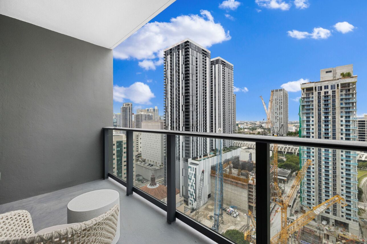 Un balcon offrant une vue sur les immeubles de grande hauteur et les grues de chantier.