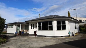 Une maison de plain-pied avec un garage, une véranda et une antenne parabolique.