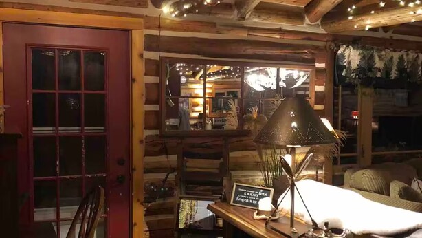 Ein gemütliches Blockhaus-Interieur mit einem Holzesstisch, einer roten Tür und einer Deckenleuchte.