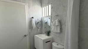 Une salle de bain équipée de toilettes, d’un lavabo et d’un rideau de douche.