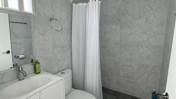A bathroom with a white toilet, a sink with a mirror, and a shower area with a curtain.