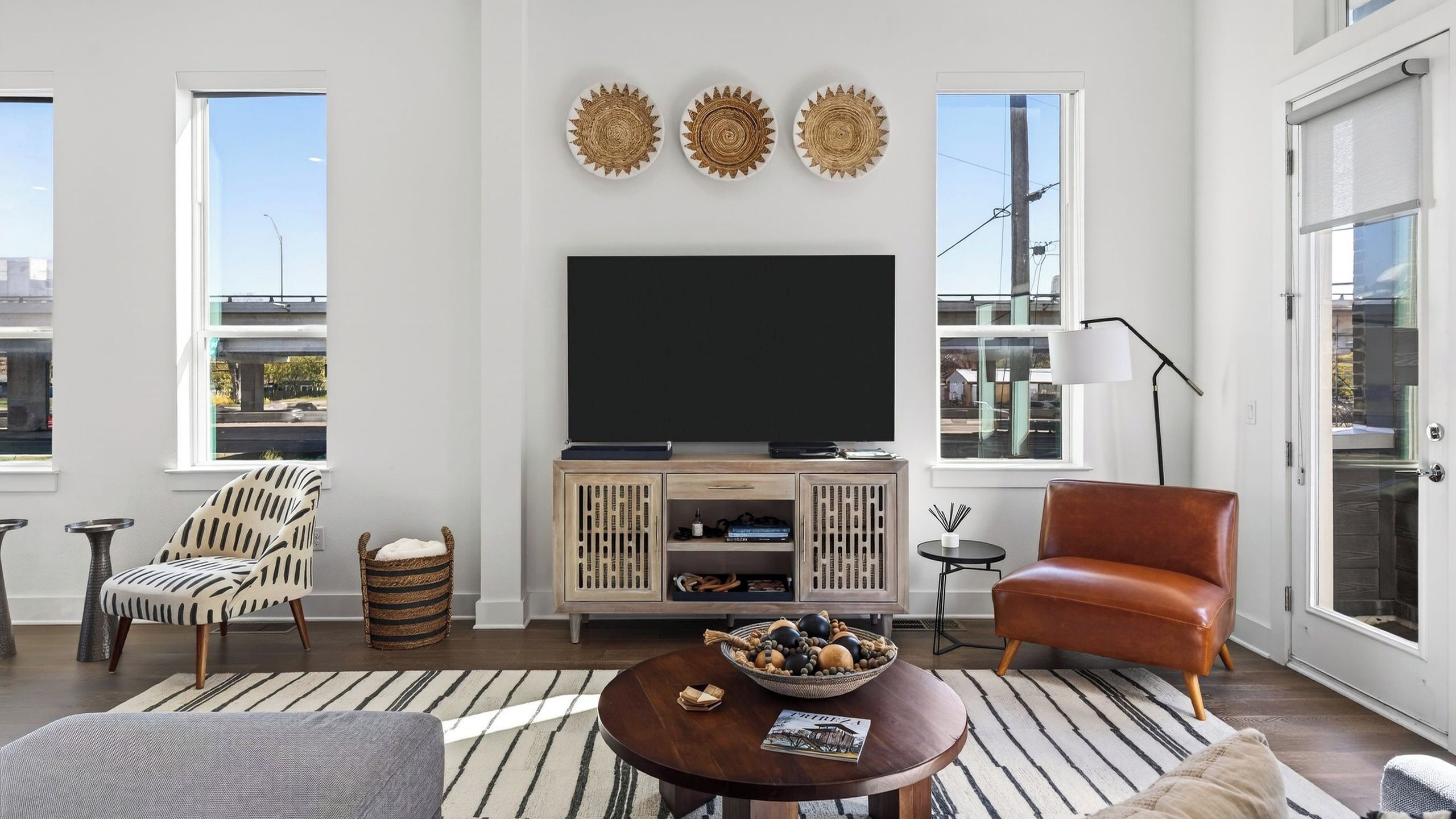 A modern living room with a flat-screen TV, a sofa, a coffee table, and a fireplace.