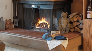 A fireplace with a bear statue, a pile of logs, and a bottle of wine. - Unique Northstar Cabin w/ Fireplace Minutes to Skiing, Trails, and Town Alpine Bend by Avantstay (Truckee)