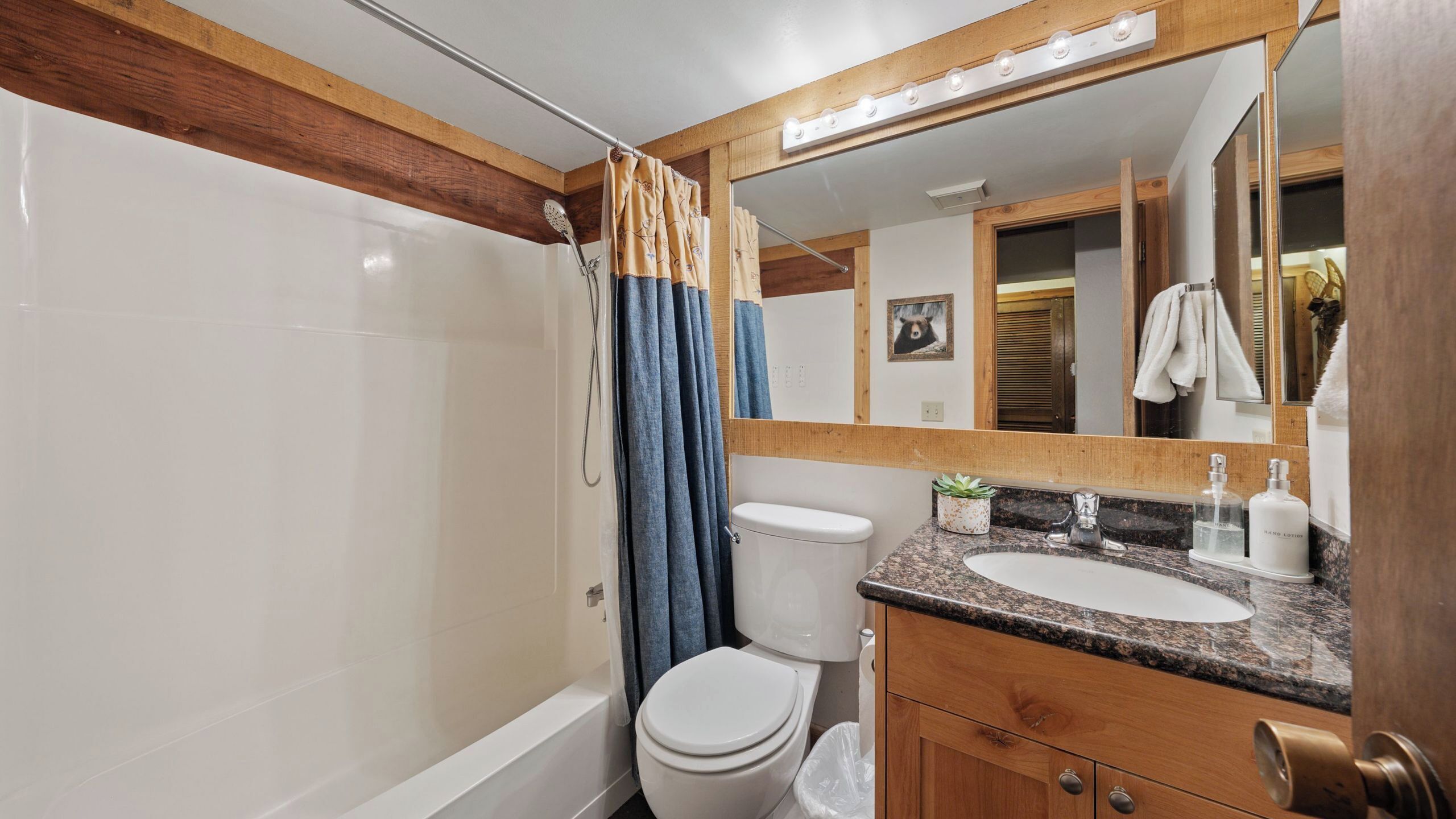 A bathroom with a shower, toilet, sink, and mirror.