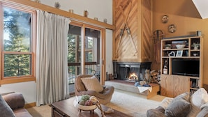 A cozy living room with a fireplace, large windows, and a wooden interior. - Unique Northstar Cabin w/ Fireplace Minutes to Skiing, Trails, and Town Alpine Bend by Avantstay (Truckee)