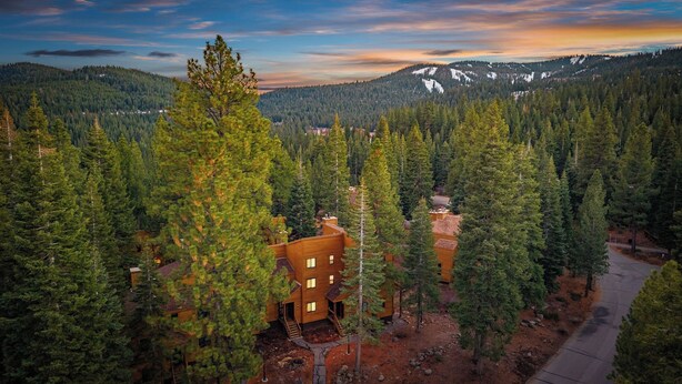 A lodge surrounded by dense forest, with a clear view of the mountains in the background. - Unique Northstar Cabin w/ Fireplace Minutes to Skiing, Trails, and Town Alpine Bend by Avantstay (Truckee)