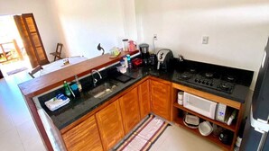 Una cucina compatta con mobili in legno, un fornello a gas, un forno a microonde e un lavandino.