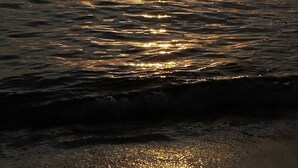 Tramonto su un mare calmo con alcune imbarcazioni.