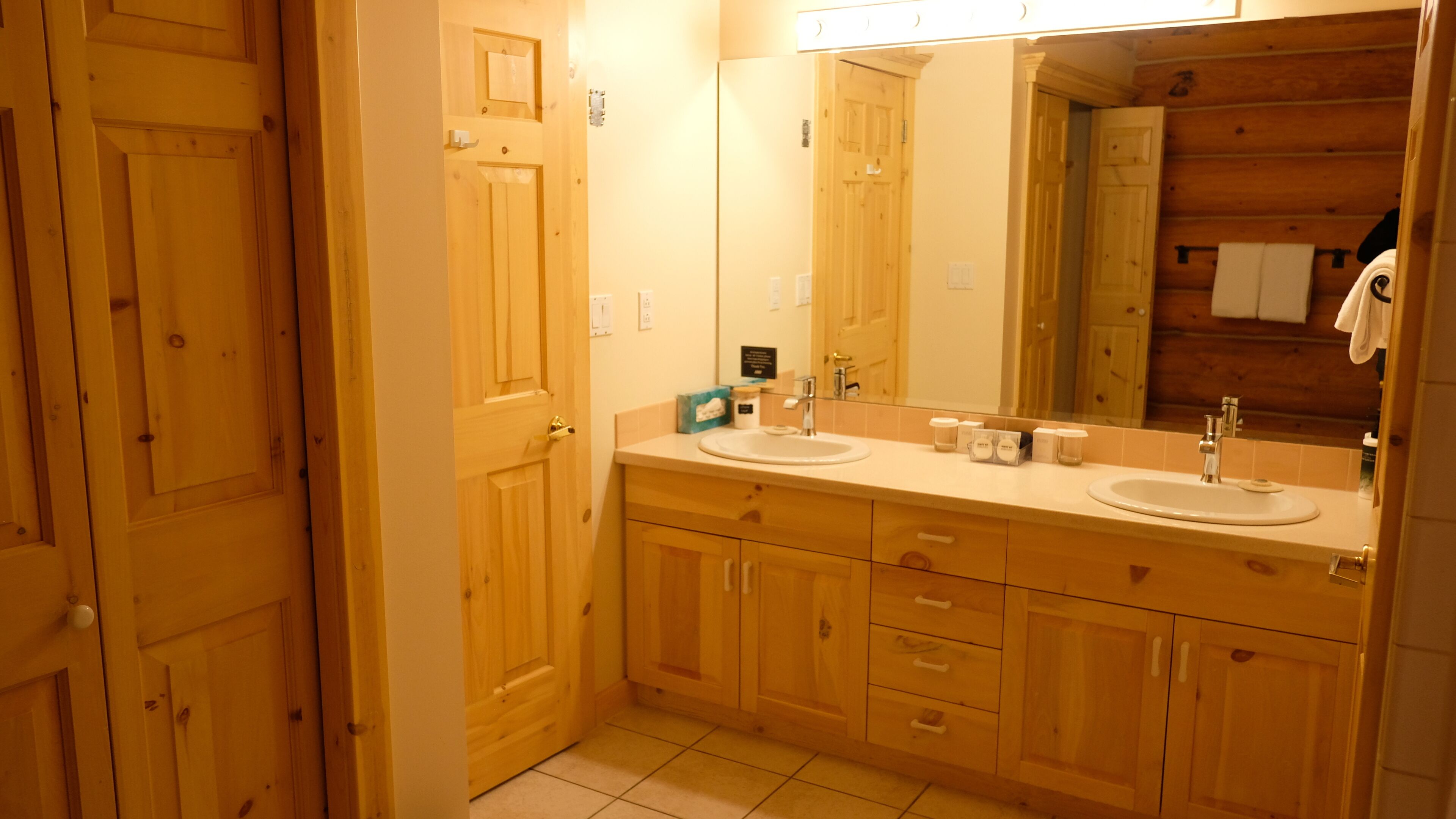 Un baño de madera con dos lavamanos, un espejo y un perchero para toallas.