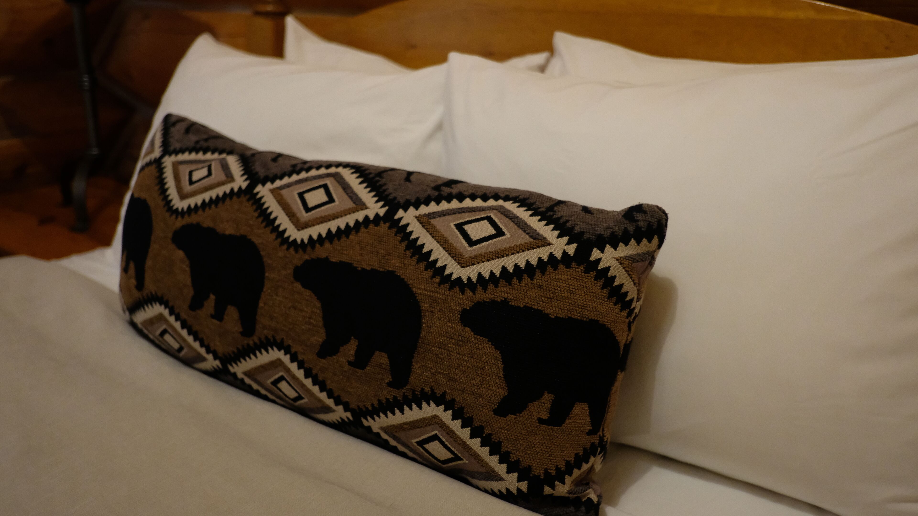 A bed with a pillow featuring a geometric pattern and animal silhouettes.