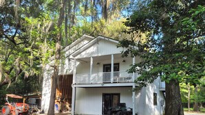 A two-story white building with a balcony, surrounded by trees and gravel. - Quiet, Secluded Getaway in Hollywood SC (Hollywood)