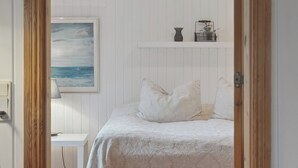 Une chambre à coucher comprenant un lit, une table de chevet, un tableau et une étagère avec des objets décoratifs.