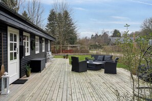 A wooden deck with outdoor furniture, a house with white trim, and a view of the surrounding landscape. - Cozy cottage near swimming lake (Borup)