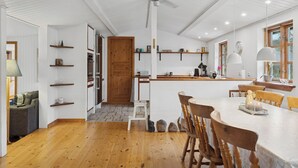 Une cuisine moderne avec un plancher en bois, des murs blancs et un îlot central doté de sièges.