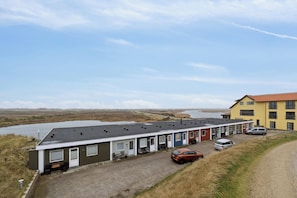 A row of single-story buildings with a gravel driveway and a parking area.