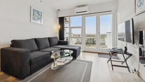 Un salon moderne avec un canapé d’angle, une table basse en verre et un grand téléviseur.